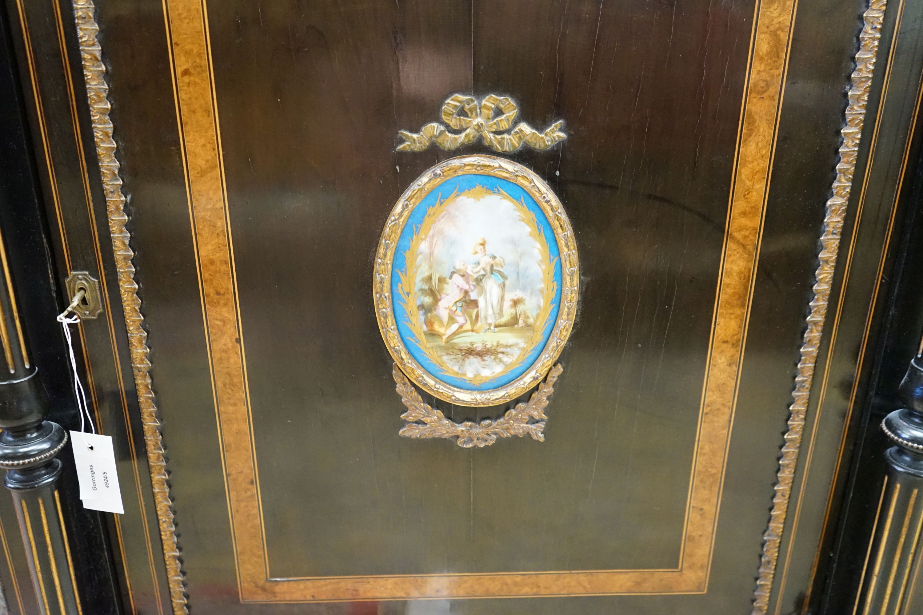 A late Victorian ebonised and amboyna banded credenza, with inset Sevres style porcelain panel, width 154cm, depth 45cm, height 107cm